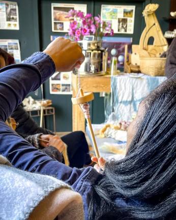 A workshop participant tries her hand at a drop spindle.