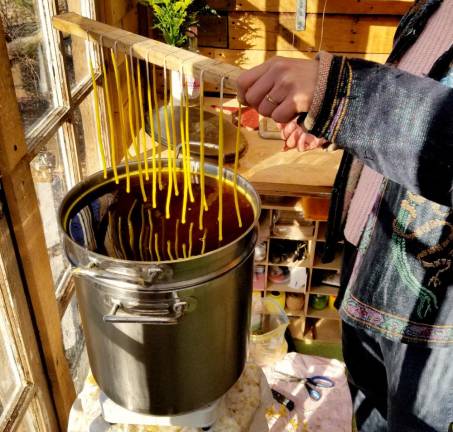 Mazzella hand dips beeswax taper candles in her Newburgh studio.