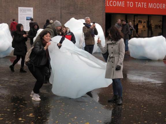Visitors interact with chunks of melting glacier outside the Tate Modern at the London installation of <i>Ice Watch. </i>
