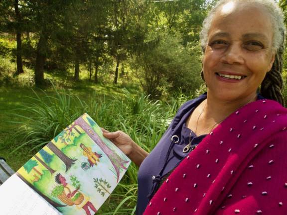 Rev. Dele at home in Middletown, NY with her children’s book, <i>Daughter of the Tree</i>, which takes a mystical look at the childhood of Sojourner Truth, bringing together themes of nature, spirituality and justice.