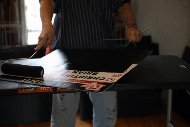 At a sign painting party in Milford, volunteers paint over and reuse old, donated political yard signs like this one from the recent school board race.