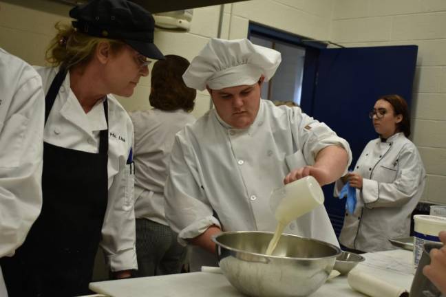 Chef Karla Link looks on as a student makes bleu cheese dressing.