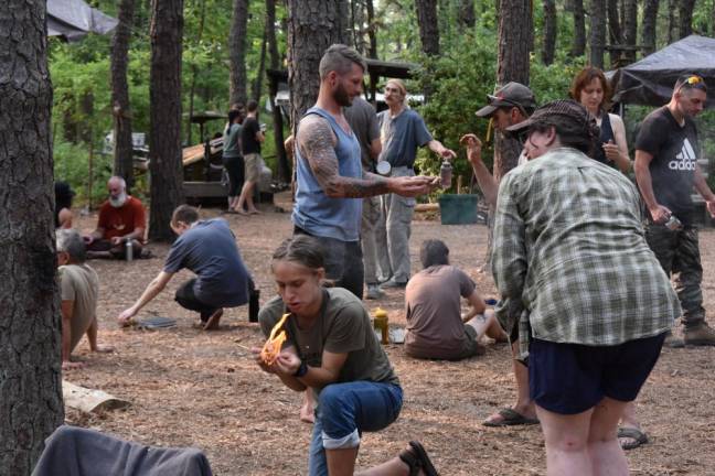 A teenager gets their first flame using a bow drill.