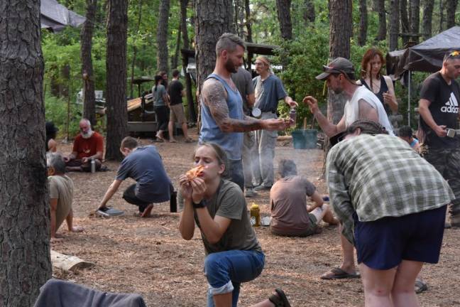 A teenage camper gets his first flame using the bow drill method of making a friction fire.