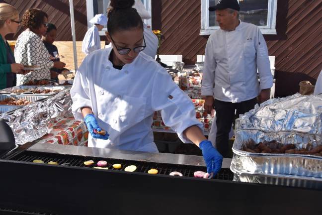 Chloe Argueta, 15, grilling veggies. In the background is Scott Zintel, her teacher, who was trained at the Culinary Institute of America.