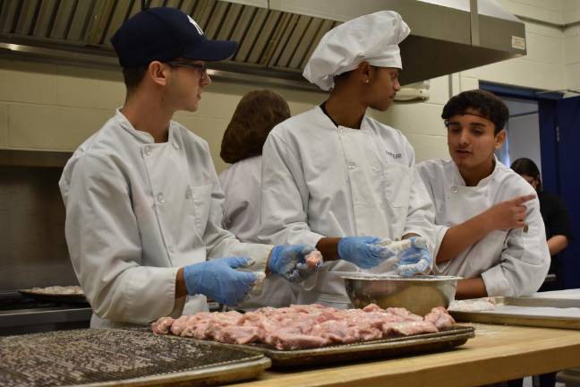 Cameron McMan, 19, on left, and Dennis Neidhard, 16, center, preparing chicken wings