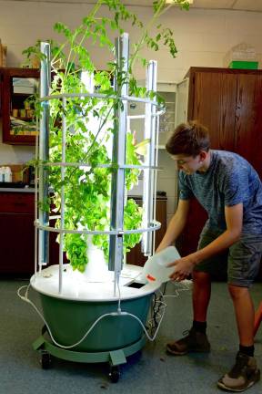 Seventh grader James Burning watering the Grow Tower at Lafayette. Photo by Melissa Shaw-Smith