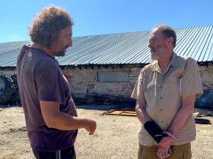 Stewart, on vacation but nonetheless armed with camera and notebook, chats with a buffalo farm worker during an impromptu farm visit in Bulgaria.