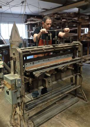 Ray cranks the screws on the hand press, drawing the wool felt up around the wooden piano hammer moldings.