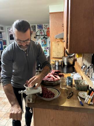 Joe Gara, a hunter, grinding venison for meatballs. After more than a decade not eating meat, he has overcome his allergy.
