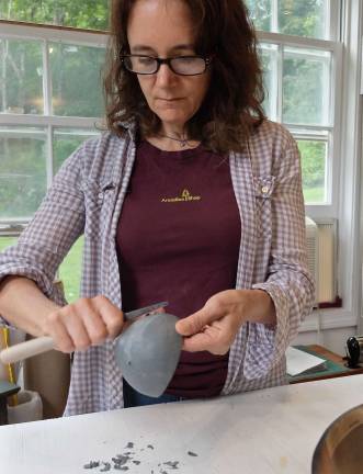Smoothing the surface of a leather-hard pinch pot before applying terra sigilatta slip