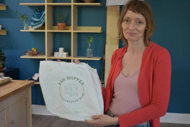 Thena with a tote featuring the original Ash Hoppers logo, which she dreamt up decades ago in response to her own struggle with eczema.