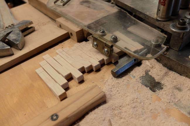 Slicing the hardwood piano hammer moldings.