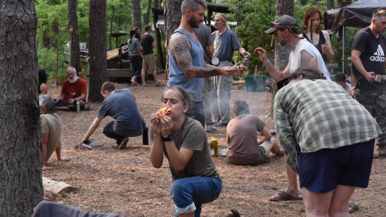 A teenage camper gets his first flame using the bow drill method of making a friction fire.